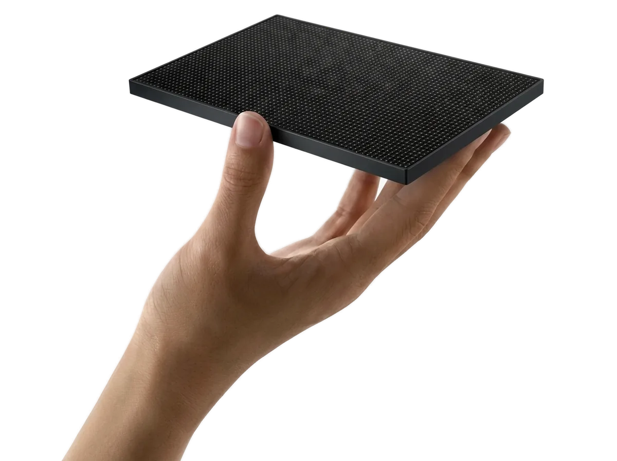 Hand presenting a black LED video wall tile module with matte black border