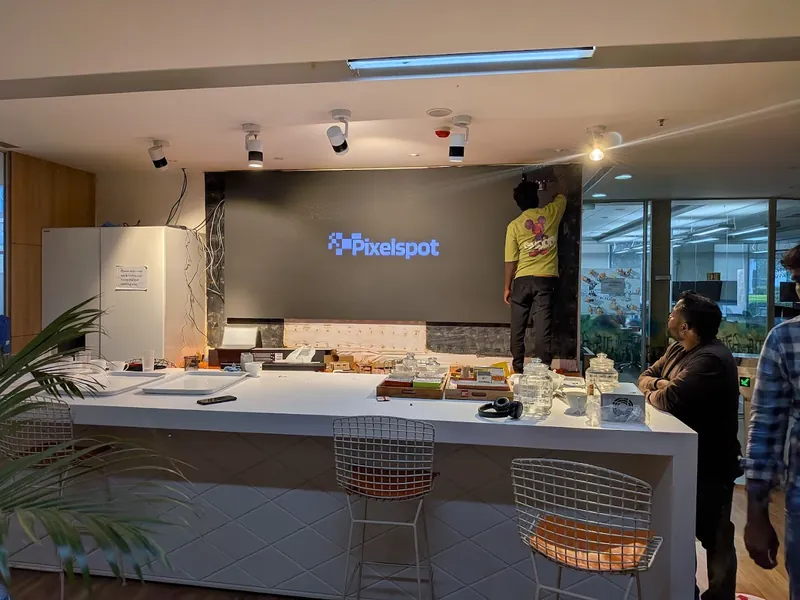 PixelSpot technician fitting the last cabinets of an indoor LED video wall in a Bengaluru office cafeteria